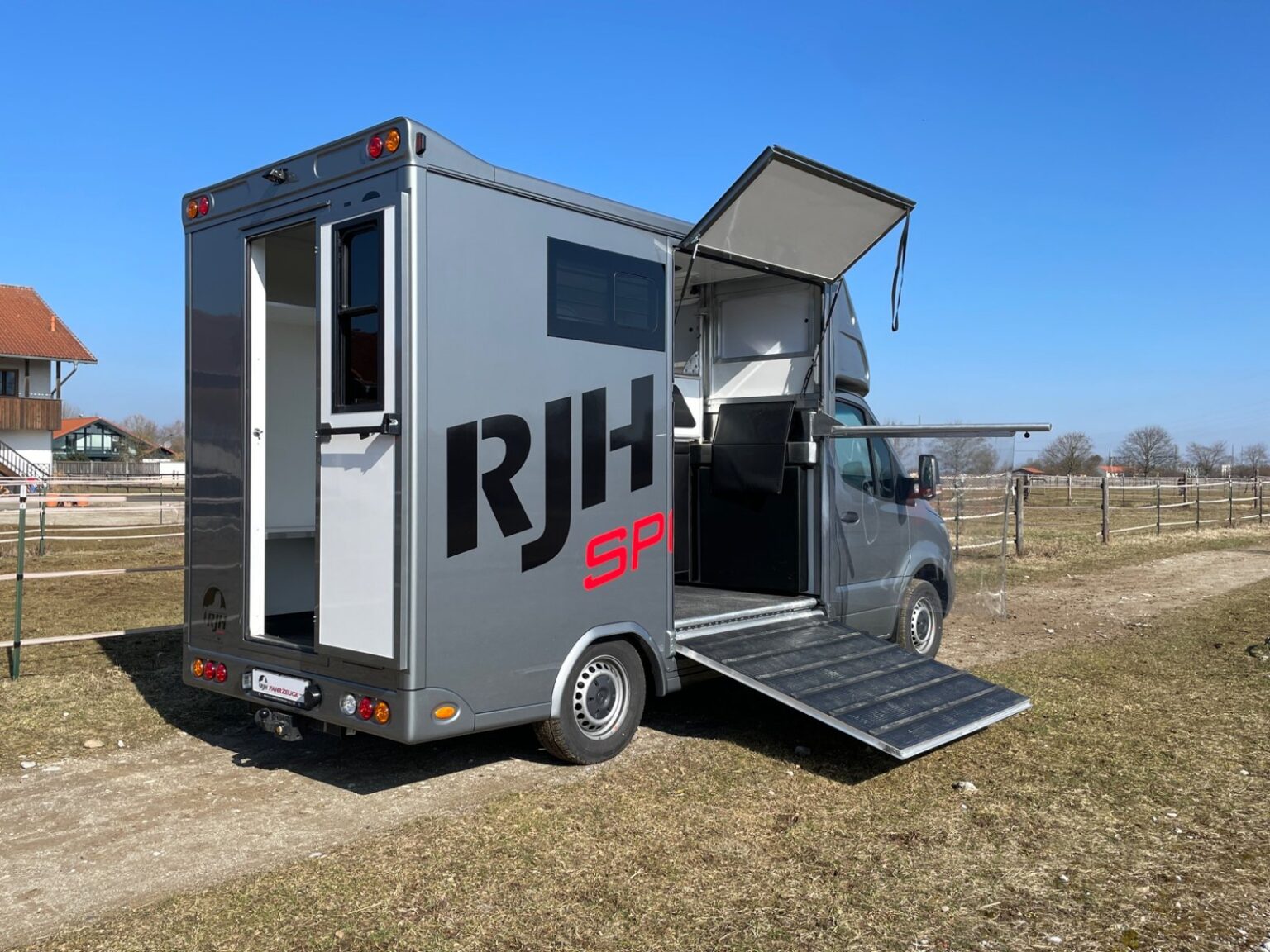 RJH 2-Pferdetransporter steht mit offener Rampe und offener Sattelkammer auf einem Feldweg